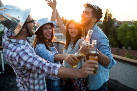 年轻的朋友在屋顶上喝酒.在派对上喝啤酒的年轻人.照片