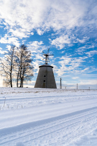 阳光明媚的冬日，空旷的乡村景观，积雪覆盖地面，背景是有趣和快乐的大废弃风车