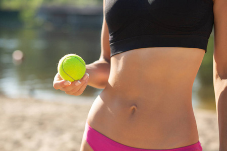 特写镜头的运动女子与完美的身体持有网球。 空的空间