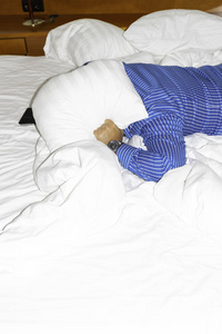 疲劳的人试图睡觉，捂住耳朵，以避免邻居在家或旅馆的噪音