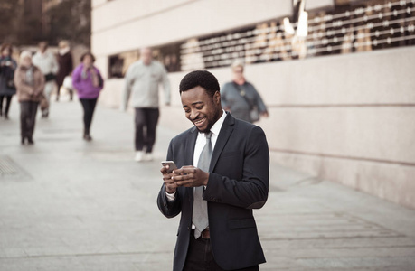年轻人穿着智能手机，在城市街道户外发送文本电子邮件或社交媒体应用程序。 快乐的商人在企业家和工作自由的通信技术之外工作。