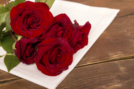 木制桌子上白色布上的一束红色玫瑰。 浪漫的概念。 平躺式顶部视图