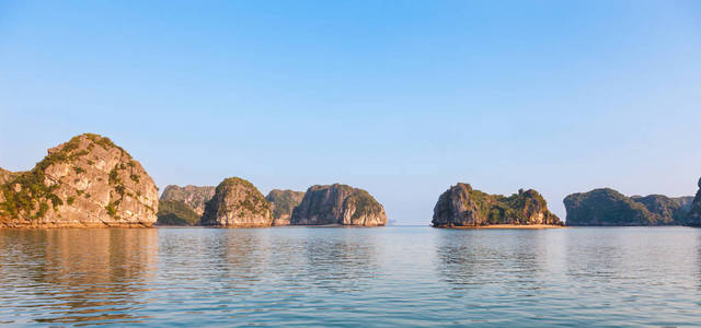 越南北部哈龙湾景观全景。 海湾由一些石灰岩整体岛屿组成，每个岛屿顶部都有从海洋中升起的厚厚的丛林植被。