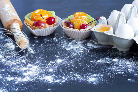 蛋糕鸡蛋放在一个托盘里,用擀面杖和一个打蛋器放在桌子上,面粉放在