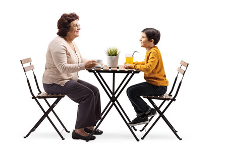 一位祖母坐在咖啡桌旁，与她的孙子在白色背景下交谈