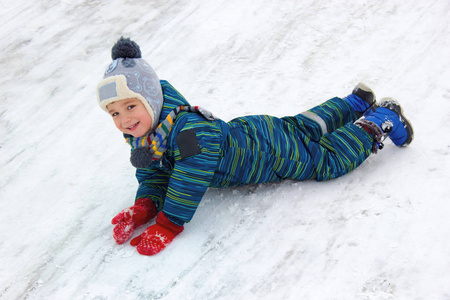 一个四岁的孩子，一个穿着漂亮冬衣的男孩，从山上骑着他的胃笑。 看看框架。