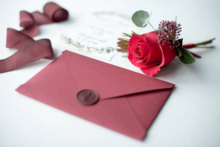 婚礼邀请函作为白色桌布上的装饰信，上面有插花