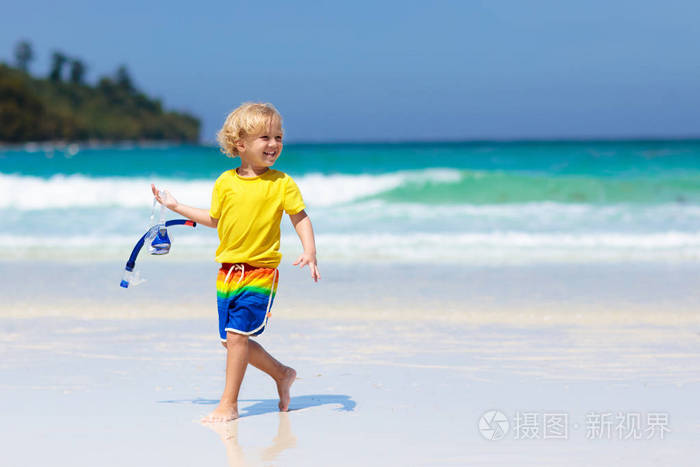 小男孩在海边玩水和沙子. 蹒跚学步的孩子在波浪中奔跑. 海滩对孩
