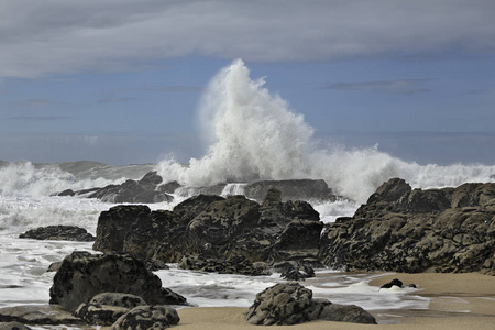 大海浪在岩石般阳光明媚的海滩上飞溅