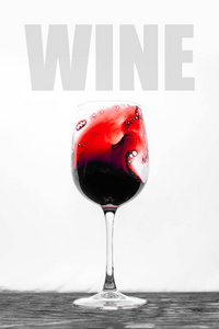 杯子里的红酒在白色的背景上飞溅着。带有文字的时尚设计卡