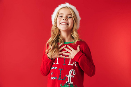 穿着圣诞服装的快乐小女孩站在红色背景下庆祝