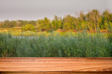 日落时，空木桌上有模糊的河边夏季背景。 可用于显示或蒙太奇产品