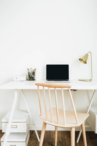 家庭办公桌面工作区，白色桌面上有笔记本电脑金灯文具。 现代室内设计理念。