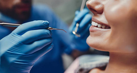 有吸引力的年轻妇女在口腔诊所与男性牙医。 健康的牙齿概念。