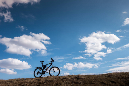 蓝天上有云的自行车剪影。 独立和自由的象征