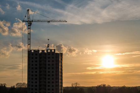 塔吊和未完工的多层高层建筑在施工现场的夕阳下美丽的夕阳