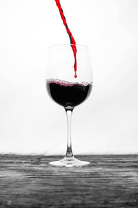 玻璃杯中的红酒在白色背景上溅起作用。 时尚设计卡