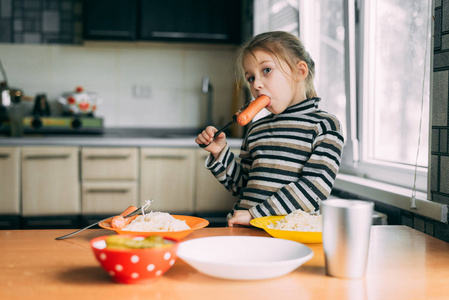咬的热狗女孩在厨房吃香肠,非常开胃照片
