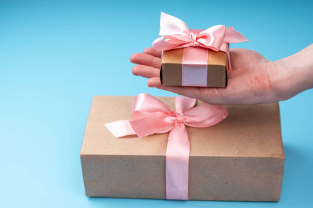 s hands holding gift box Packed in Kraft paper with pink ribbon 