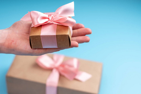 s hands holding gift box Packed in Kraft paper with pink ribbon 