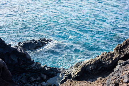 大西洋清澈的蓝色水和冷却的熔岩。 兰塞罗特岛西班牙。
