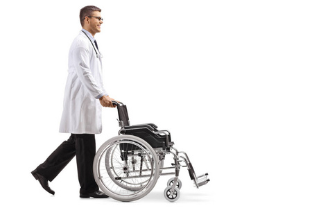 一位年轻的男医生推着一个被隔离在白色背景上的空轮椅的全长镜头