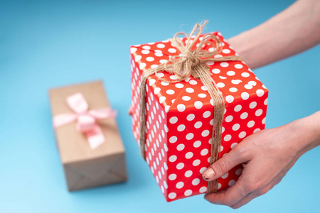 s hands holding gift box Packed in red polka dot paper on blue b