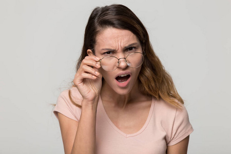 困惑的妇女降低眼镜看着相机与愤慨照片