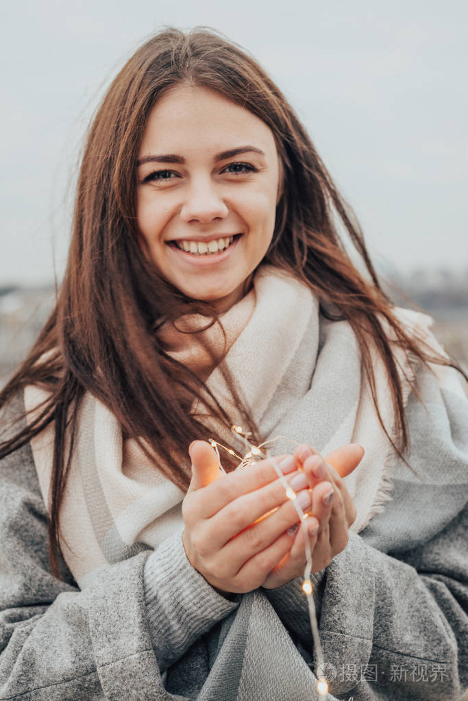 美丽的女孩长得笔直微笑着双手捧着温暖的花环