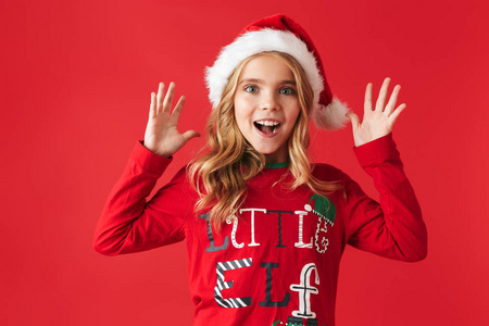 穿着圣诞服装的活泼可爱的小女孩站在红色背景下，庆祝
