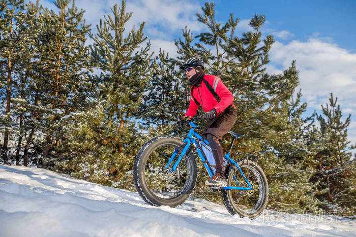 一个人骑着一辆山地自行车,在雪地上戴着厚厚的轮胎和头盔. 胖自行车.