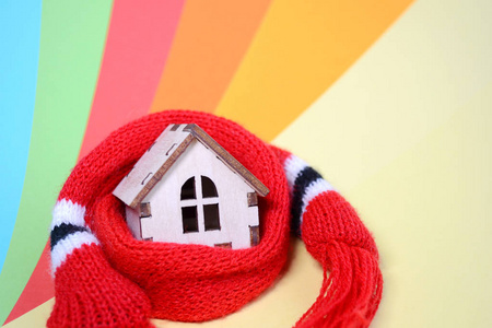 木制玩具房子，有窗户，戴着红围巾，戴着彩虹色的背景暖房，房子隔热，空间特写