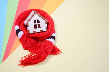 戴着红围巾的木制玩具房子，有彩虹色背景的暖房，房子的隔热空间