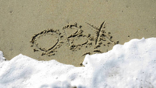 当波浪在字母上冲刷时，写在沙子上的OB X