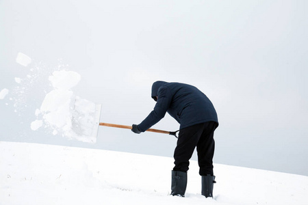 一个人在大雪后从屋顶上除雪