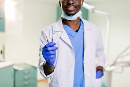 一位非裔美国人牙医手里拿着镜子和探针