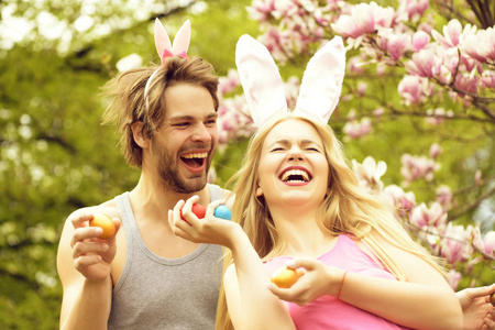 男人和小女孩微笑着拿着鸡蛋的兔子耳朵
