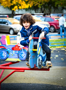 小男孩在户外操场上玩旋转木马。 春季或秋季儿童积极运动休闲。 幼儿园或学校院子。 幼儿活动