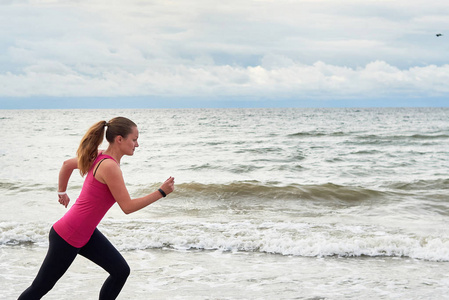 运动女子跑在海边复制空间。 女跑步者在夏季晨边观看。 健康生活方式概念