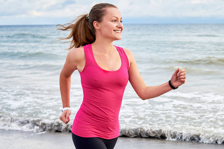 微笑的运动女人跑在海边复制空间。 夏天早上跑步的女性。 健康生活方式概念