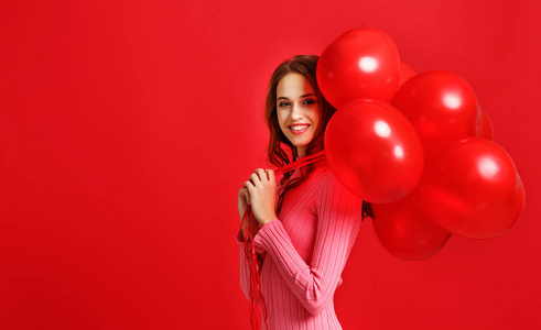 年轻美丽的情感女孩，穿着粉红色的裙子，红色的背景上有红色的气球