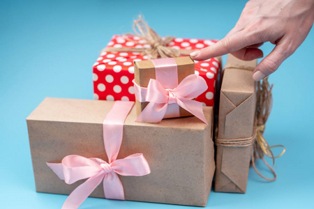 s hands holding gift boxes Packed in Kraft paper with pink ribbo