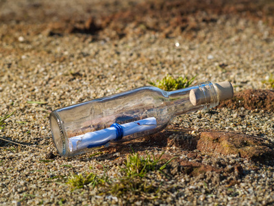 海滩上一个水晶瓶里的短信,里面有水和沙子照片