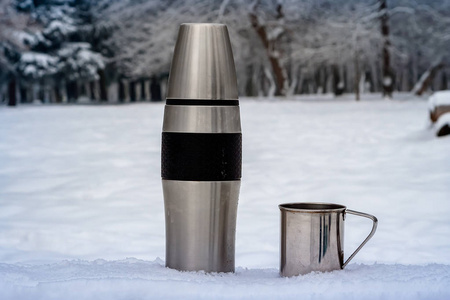 冬天室外的热水瓶和杯子。 徒步旅行