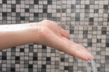 手的软选择焦点和水滴从淋浴与图案背景