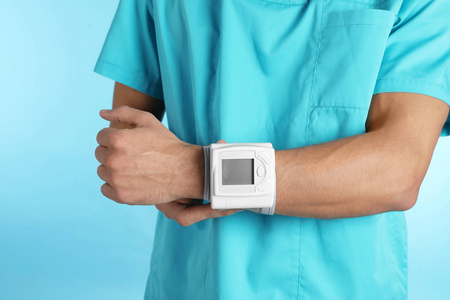 男性医生使用血压监测仪进行彩色背景特写。 医疗器械