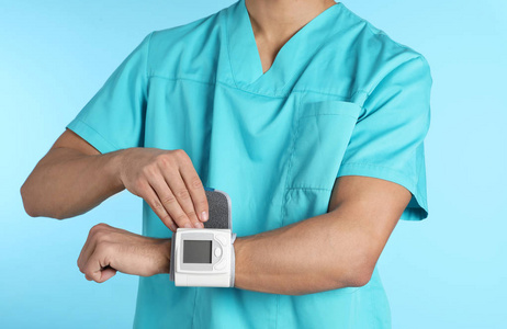 男性医生使用血压监测仪进行彩色背景特写。 医疗器械
