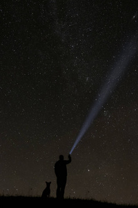 男人看着星星，他的狗在他身边