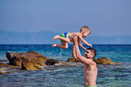 两岁的蹒跚学步的男孩和父亲在海滩上