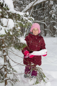 小女孩在冬天森林附近雪云杉